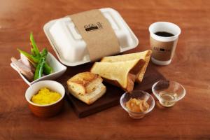 - une table avec un plateau de sandwichs et une tasse de café dans l'établissement 蓼科BASE kitchen,spa&hotel, à Chino