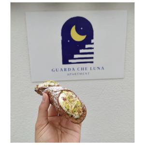una persona sosteniendo un pedazo de comida en su mano en Guarda che Luna Apartment en Porto Empedocle