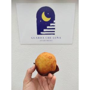 a person holding a doughnut in front of a sign at Guarda che Luna Apartment in Porto Empedocle