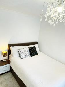 a white bed with two pillows on it in a bedroom at Khan's Living Lakeside Drive Cyncoed Cardiff in Cardiff