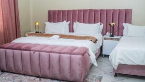 a hotel room with a large pink bed and a couch at Henry George Guest House in Pretoria