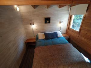 a small bedroom with a bed in a wooden cabin at Home Cabaña Grande de Angostura in Villa La Angostura