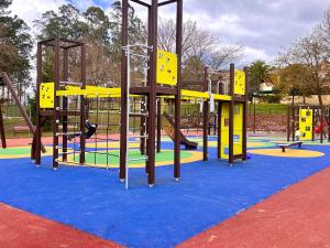 a playground with yellow and blue equipment in a park at Los Sauces, adosado a 10 minutos de Oviedo y 15 de Gijon in Llanera
