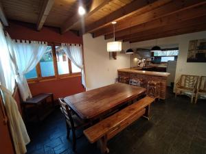 a dining room with a wooden table and a kitchen at Home Cabaña Grande de Angostura in Villa La Angostura