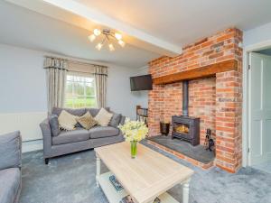 a living room with a brick fireplace and a couch at Gardeners Cottage in Kiddemore Green