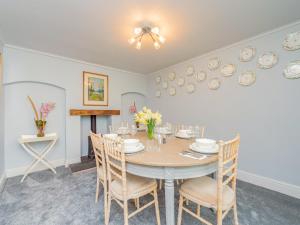 une salle à manger avec une table, des chaises et des assiettes murales dans l'établissement Gardeners Cottage, à Kiddemore Green