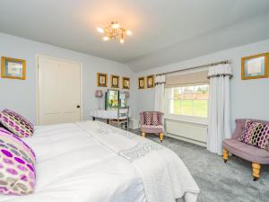 a bedroom with a large white bed and two chairs at Gardeners Cottage in Kiddemore Green