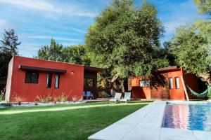 a red house with a swimming pool and a yard at ESPACIO RAKU in Ciudad Lujan de Cuyo