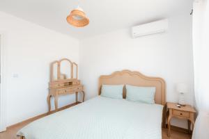 a white bedroom with a bed and a night stand at Casa Mavis in Mahmudia