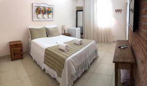 um quarto com uma cama grande e toalhas em Pousada Tortugas no Guarujá