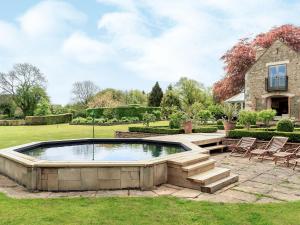 a pool in a yard with chairs and a house at Cotswolds Farm in Miserden