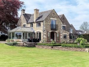 a large stone house with a lawn at Cotswolds Farm in Miserden