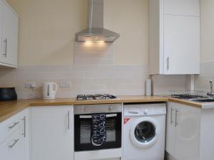 a kitchen with white cabinets and a washing machine at Kirkview in Dundonald