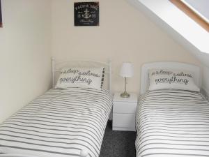 two beds in a bedroom with white walls at Kirkview in Dundonald