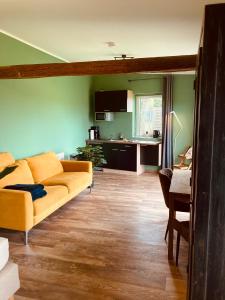 a living room with a yellow couch and a kitchen at Hotel Zum Alten Schlagbaum, Garni in Wegberg