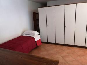 a bedroom with white cabinets and a red bed at Parte di casa con giardino e piscina in Pietrasanta