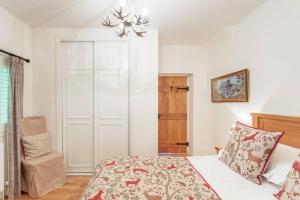 een slaapkamer met een bed en een stoel erin bij The Mews - a cottage with a spectacular lake view in Port of Menteith