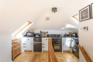 a kitchen with white cabinets and black appliances at The Mews - a cottage with a spectacular lake view in Port of Menteith