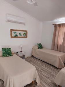 two beds in a room with white walls and wooden floors at Complejo Amarelo in Chajarí
