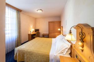 una camera d'albergo con letto e lampada di Hotel Relais Orsingher a Fiera di Primiero