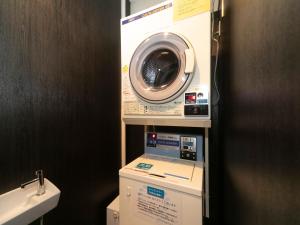 神戸市にあるアパホテル〈神戸三宮〉　　のバスルーム(棚に洗濯機、乾燥機付)