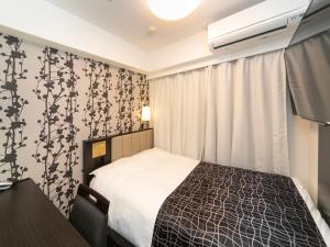 una camera d'albergo con letto, scrivania e tende di APA Hotel Kobe-Sannomiya a Kobe