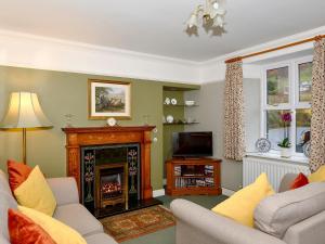 a living room with a fireplace and a tv at Mollys Cottage in Glenridding