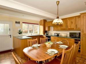 a kitchen with a wooden table and wooden cabinets at Mollys Cottage in Glenridding