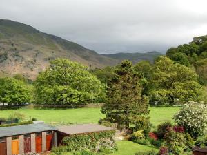 a house in a field with mountains in the background at Mollys Cottage in Glenridding