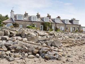 a row of houses on a rocky beach at Shore Cottage in Carsluith