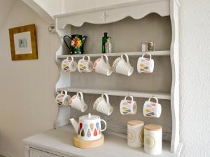 a shelf filled with cups and mugs on top of a counter at Shore Cottage in Carsluith