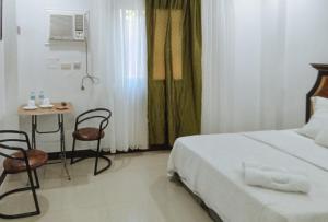 1 dormitorio con 1 cama, mesa y sillas en RedDoorz at Caree Boutique Hotel Bulan Sorsogon en Bulan