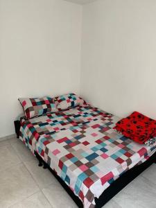 a bed with a checkered blanket on top of it at Apartamento Cerca al Parque el Café in Montenegro