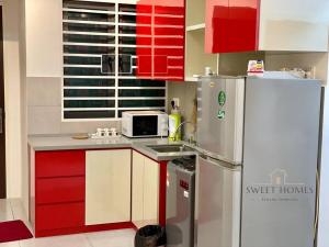 La cuisine est équipée de placards rouges et d'un réfrigérateur. dans l'établissement R&W 1-5pax B'worth Prai #Netflix #6minPenangBridge, à Perai