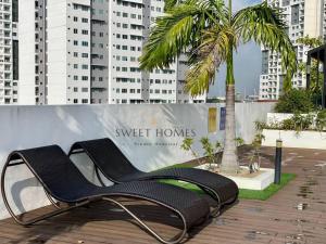 2 chaises assises sur une terrasse avec un palmier dans l'établissement R&W 1-5pax B'worth Prai #Netflix #6minPenangBridge, à Perai
