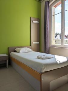 a green bedroom with a bed with a window at Auberge des Remparts in Péronne