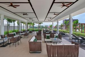 an outdoor restaurant with tables and chairs and palm trees at Courtyard by Marriott Melaka in Melaka