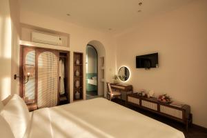 um quarto com uma cama, uma secretária e uma televisão em RUBENS BOUTIQUE HOTEL em Phan Thiet
