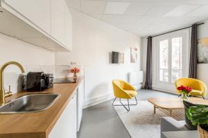 eine Küche mit einem Waschbecken und gelben Stühlen in einem Zimmer in der Unterkunft Cosy 3 bedrooms apartment - Le Marais in Paris