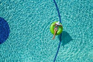 een vrouw drijvend op een vlot in een zwembad bij Minos Mare Royal in Platanes