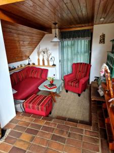 Kauperhaus في بورغ (سبريوالد): غرفة معيشة مع أريكة حمراء وكرسيين حمراء