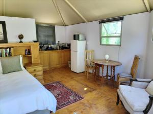 ein Schlafzimmer mit einem Bett und einem Tisch sowie eine Küche in der Unterkunft Glamping at The Well in Franschhoek in Franschhoek