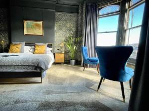 um quarto com uma cama e uma cadeira azul em The Earlsdale Bed and Breakfast em Ilfracombe