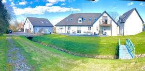 a house on a hill with a river in front of it at Druid House B&B in Inverness