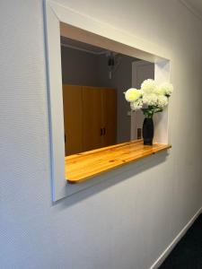 a mirror with a vase of flowers on a shelf at Traume vandrarhem in Visby