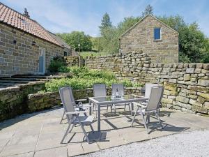 a table with four chairs and a stone wall at North Range in Castleton