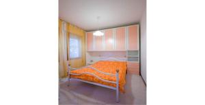 a bedroom with a bed with an orange blanket at Homely apartment close to the beach - Beahost in Rosolina Mare