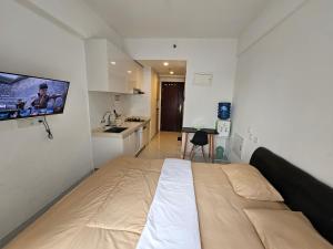 a bedroom with a large bed with a tv on the wall at Apartement Sky House BSD By LiviRooms in Cilandak