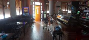a restaurant with a bar with stools and a slot machine at Hostal San Julian in El Herrumblar