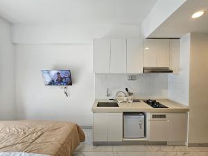 a small kitchen with a sink and a stove at Apartement Sky House BSD By LiviRooms in Tjilandak